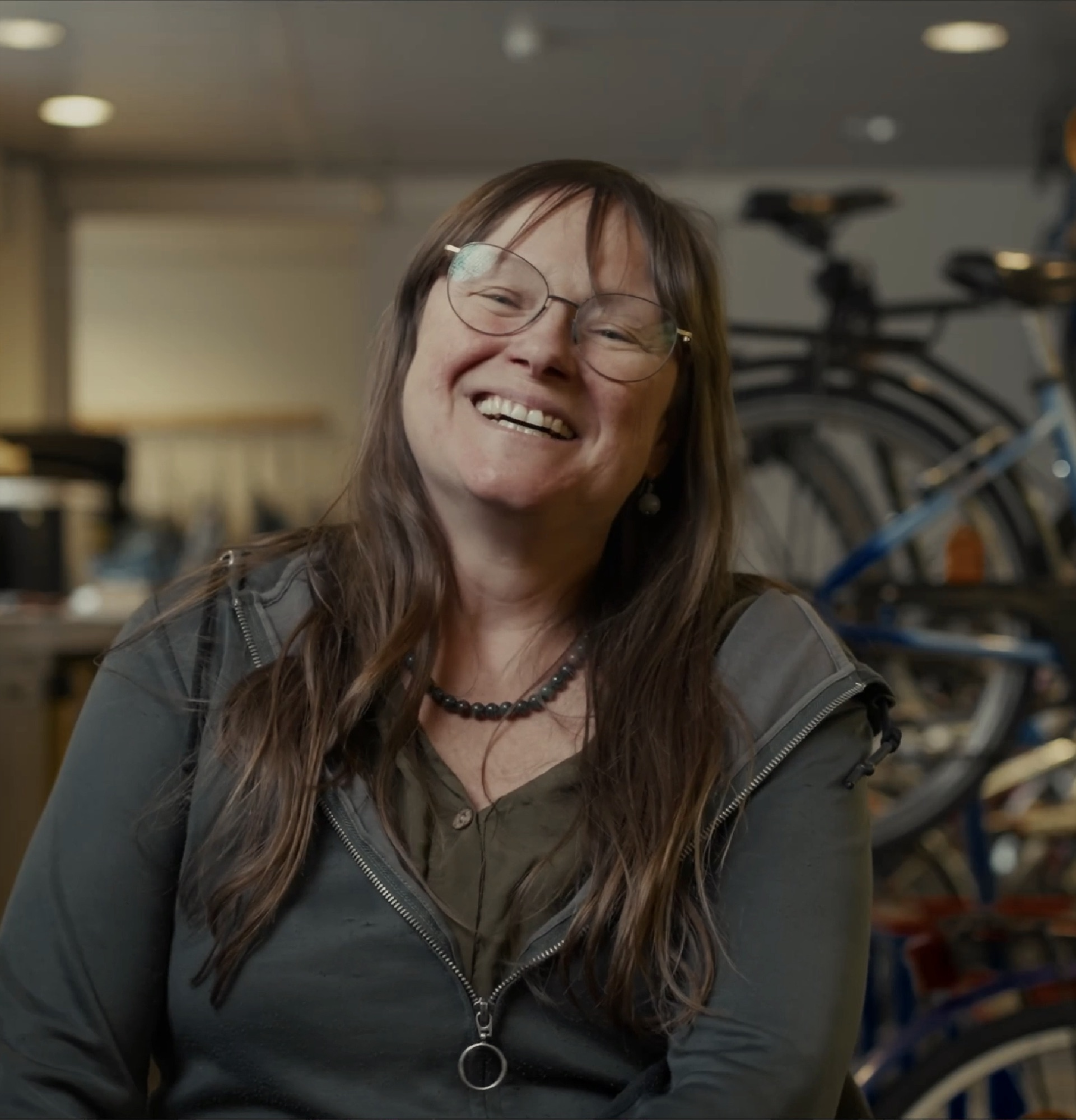 A woman laughing in a bicycle workshop: a still from the Op Wielekes film